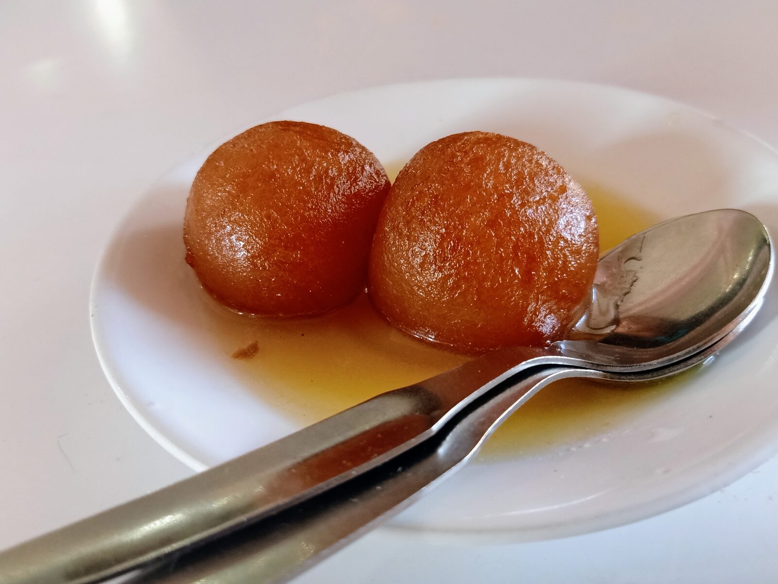 Warm gulab jamun dumplings soaked in rose and cardamom syrup